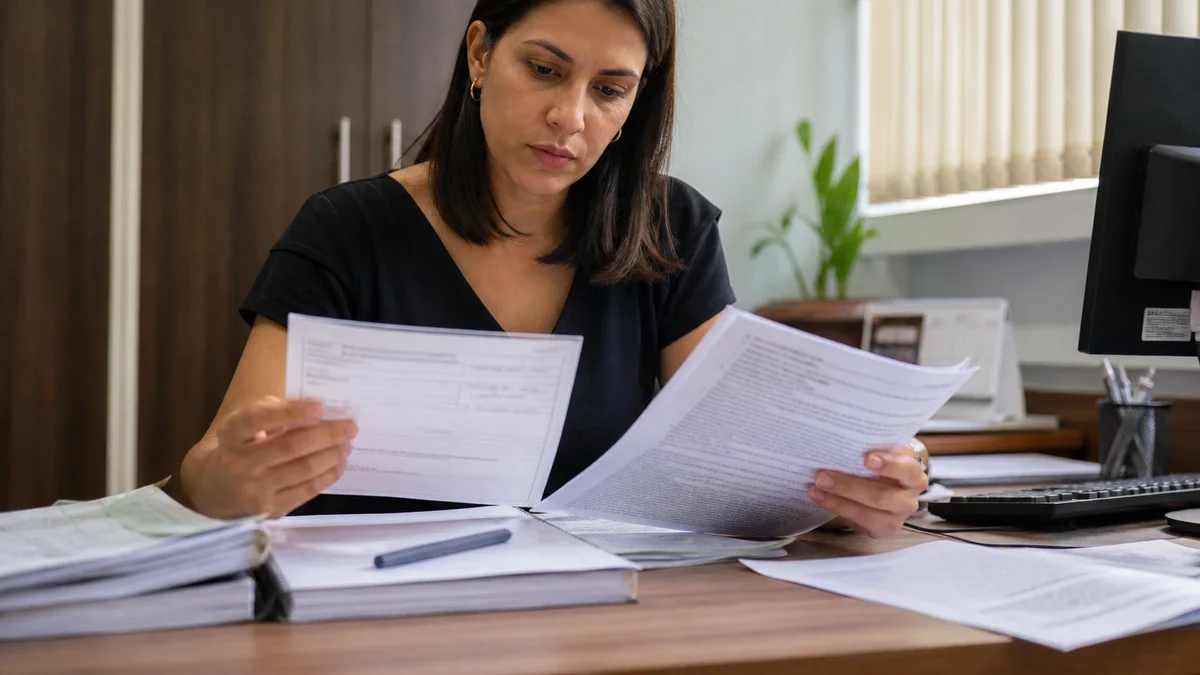 Trabalhador confere metas de PLR, holerite e documentos do acordo coletivo na mesa